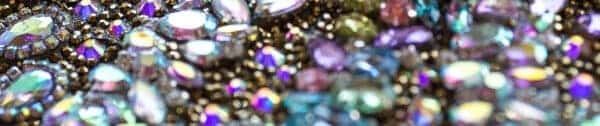 Assorted multicolored gemstones and crystals clustered together, reflecting light with iridescent and metallic tones, reminiscent of the vibrant palette found on a classic 1950s sundress.